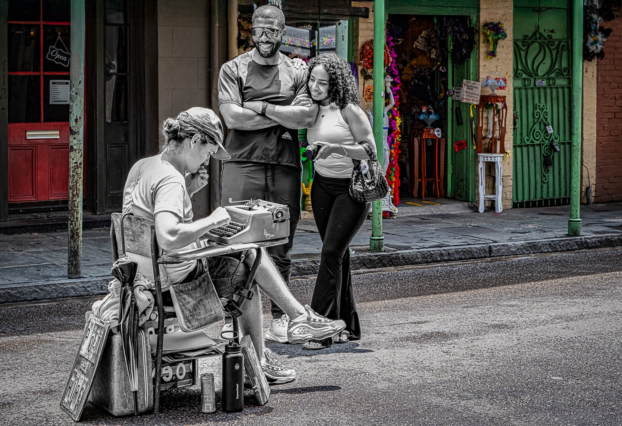 Just up Royal from Café Beignet, a poet sits behind a folding table, performing in his own way—clicking out poems on a vintage typewriter. A man and woman watch, smiling, as he creates something just for them. There’s no mic, no shouting—just the sou