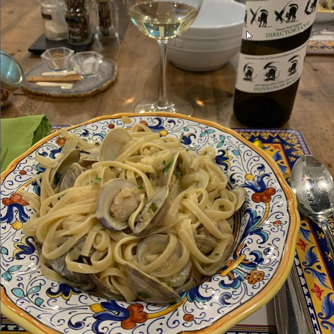 colorful dish of linguine with clams and glass of white wine