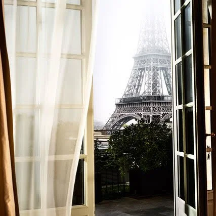 view of the Eiffel Tower out a window with a sheer curtain
