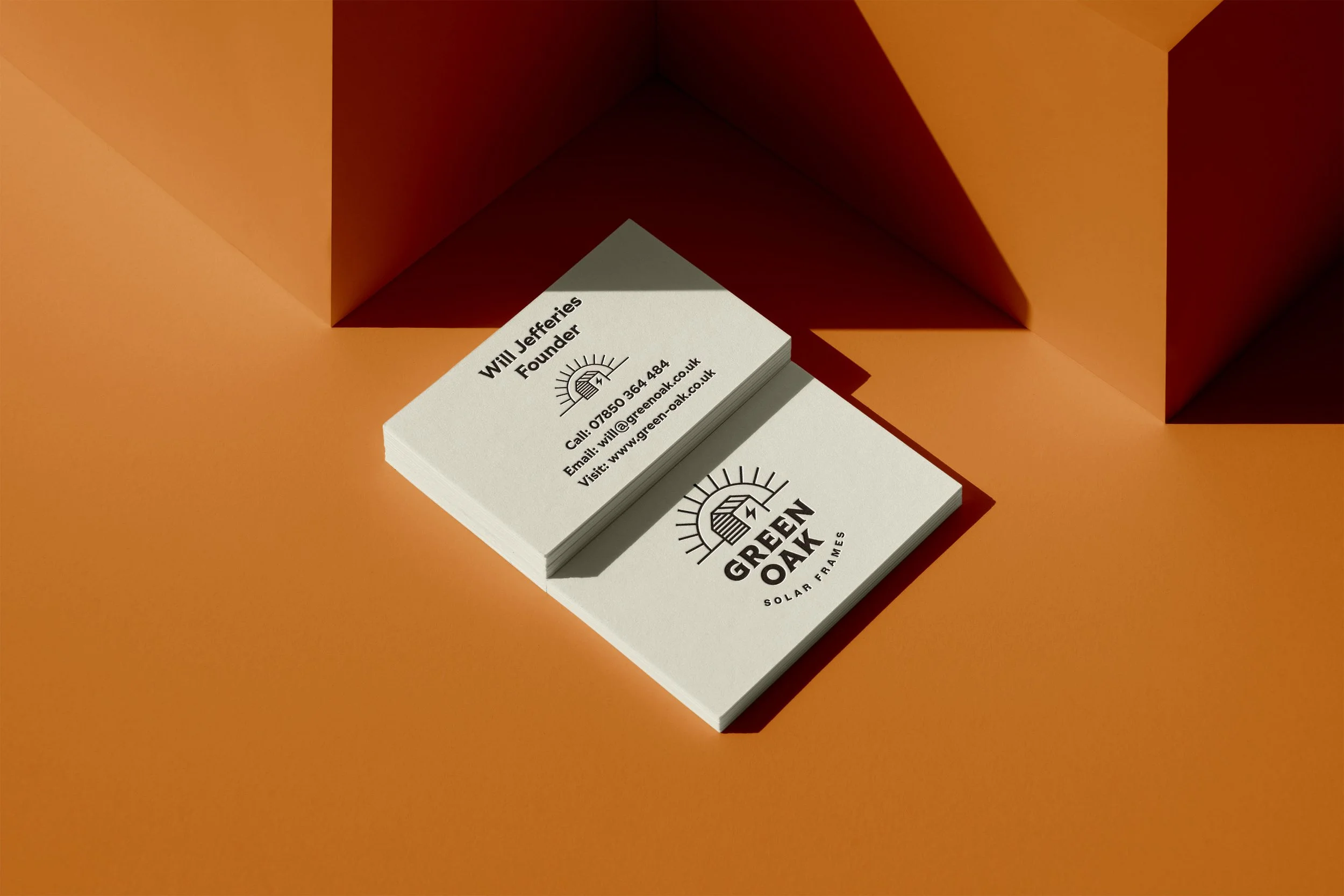 Stack of business cards on an orange background with contact information for "Green Oak Solar Frames" and a sun logo.
