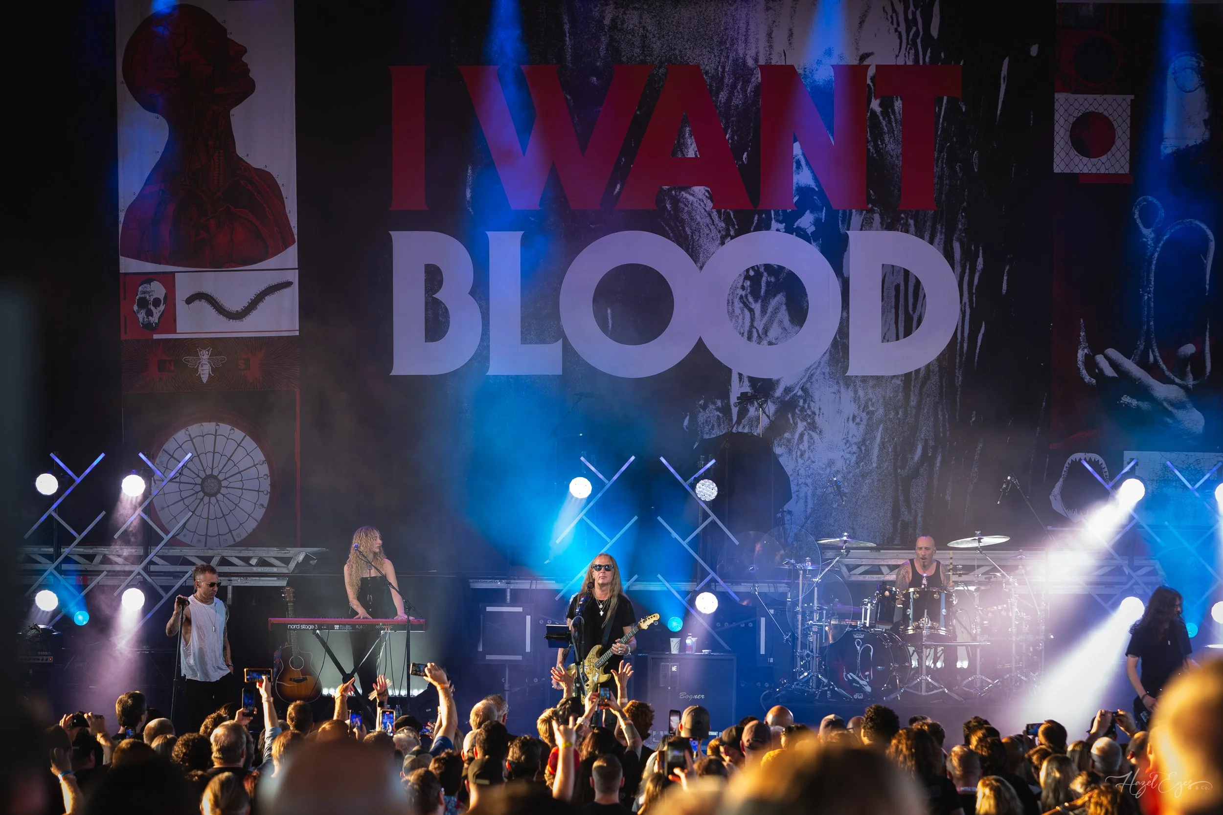 Jerry Cantrell in concert at Michigan Lottery Amphitheatre at Freedom Hill in Sterling Heights, MI on August 16, 2024. Guitarist on stage backlit with bright stage lighting with audience in foreground. Full stage shot showing the "I WANT BLOOD" stage