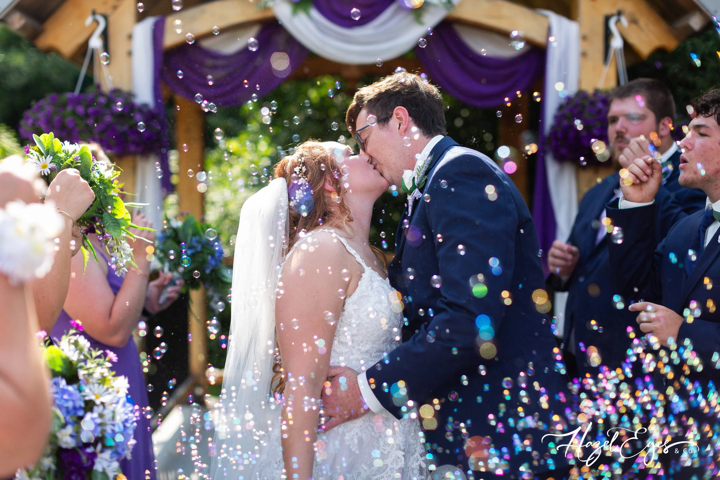 Michigan country barn wedding. Bridal and groom kissing. bride dress. groom suit. bubble photo. wedding ceremony. Michigan wedding photographer. Hazel Eyes & Co. July wedding. Our Little Girl Event Barn Clifford, MI 48727