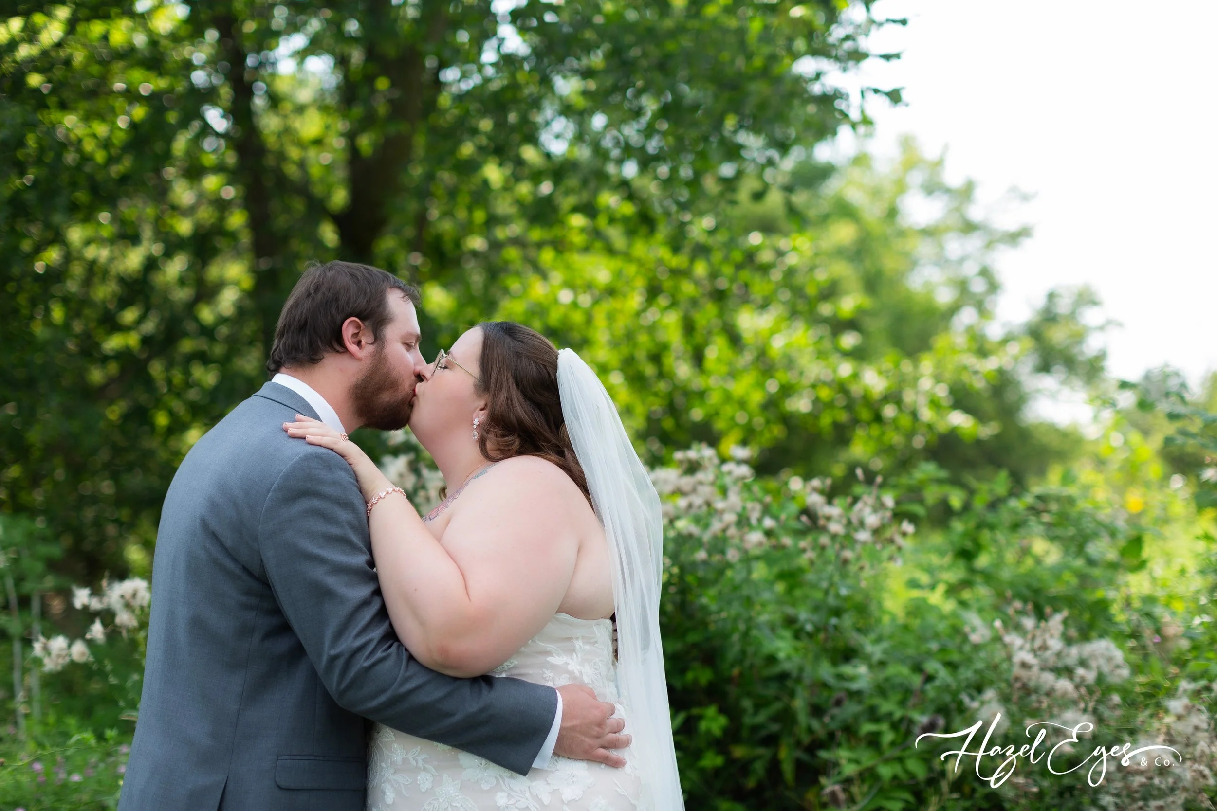 Michigan outdoor wedding. bride and groom photo. bride dress. groom suit. bride’s dress. Michigan wedding photographer. Hazel Eyes & Co. August wedding. Summer wedding.  Creekside Acres Event Barn Goodrich, MI 48438 Private vows bride and groom kiss