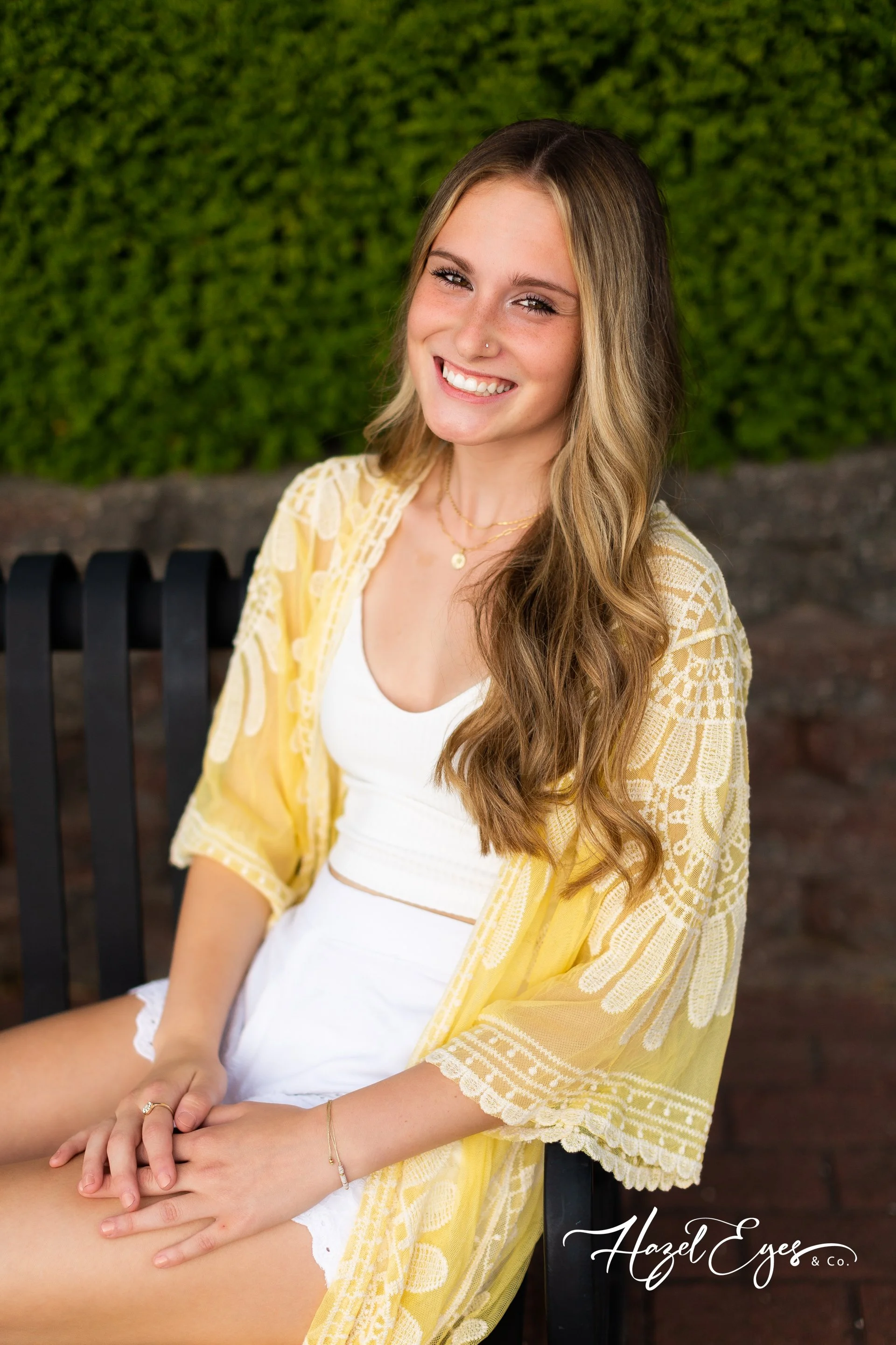 high school girl in yellow sitting on bench posing for photo
