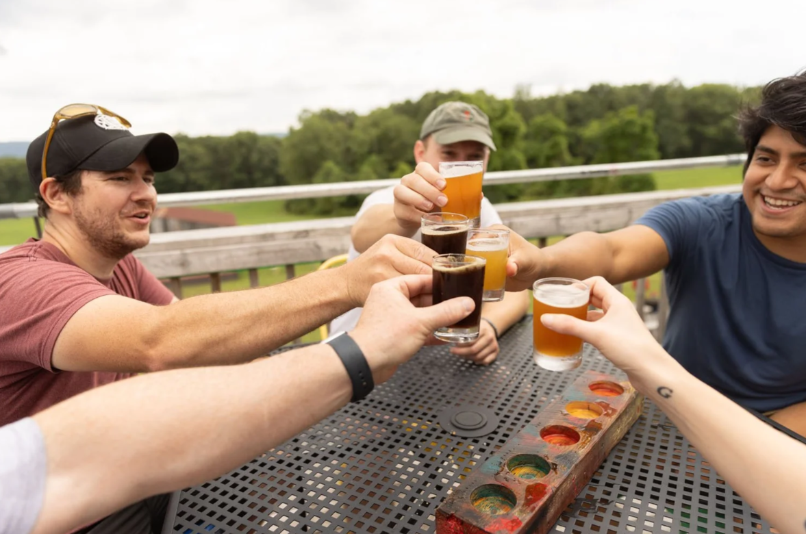 A group of friends enjoying drinks together at an outdoor patio, raising their glasses in a toast.
