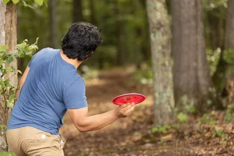 Man throwing a frisbee in a wooded area