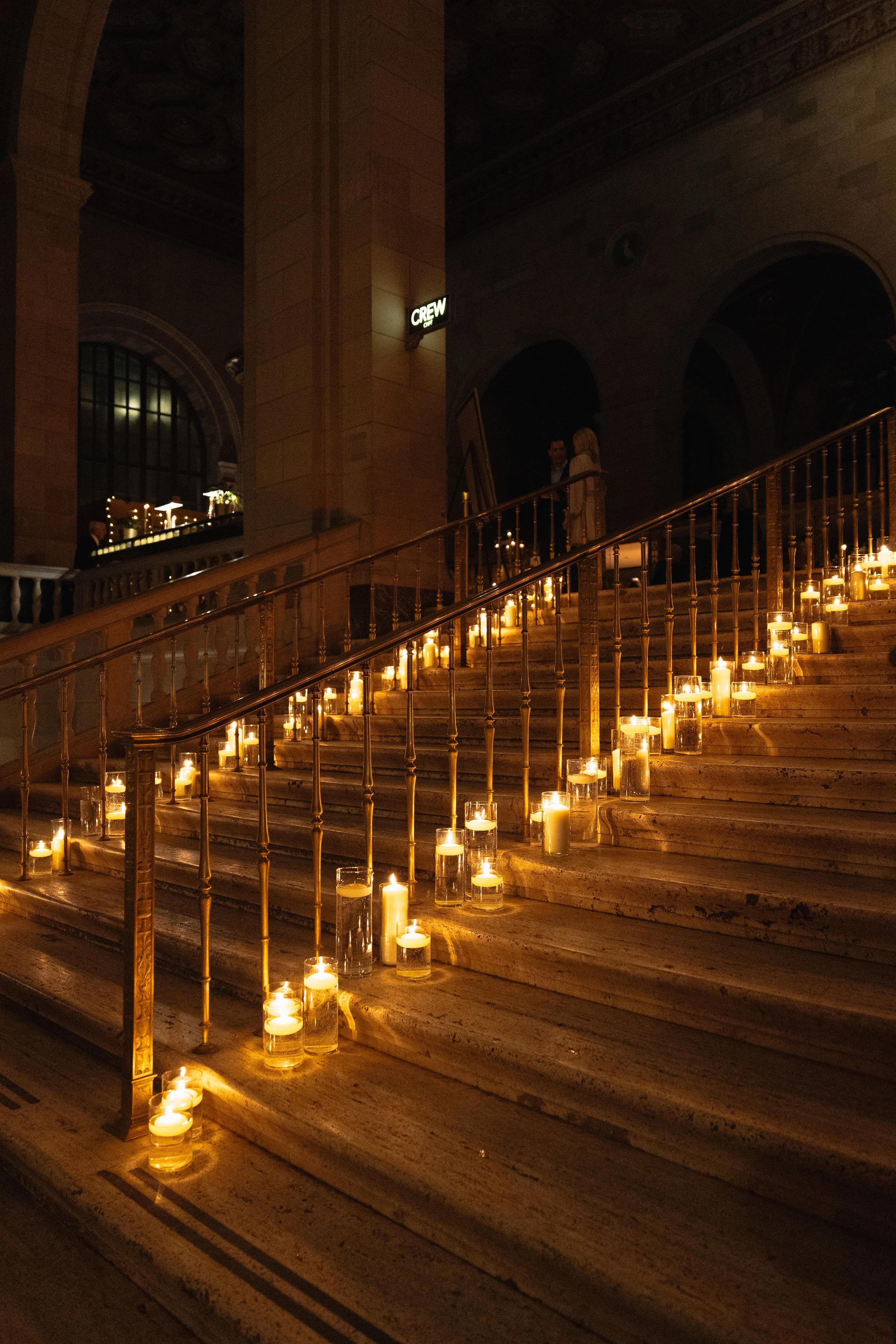 Dimly lit staircase decorated with numerous candles in glass holders.