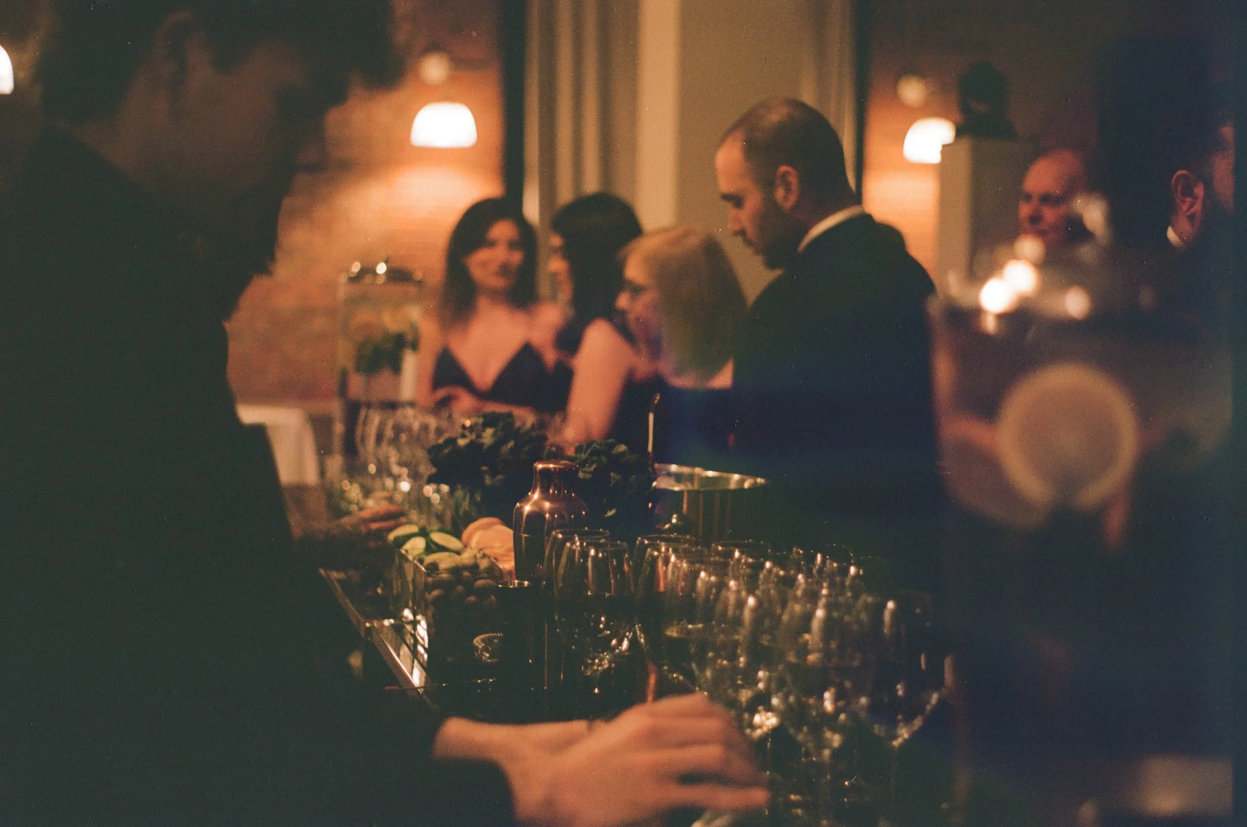 A quiet moment at the bar, captured on 35mm during an intimate Montreal wedding—grain, glow, and the soft hum of celebration