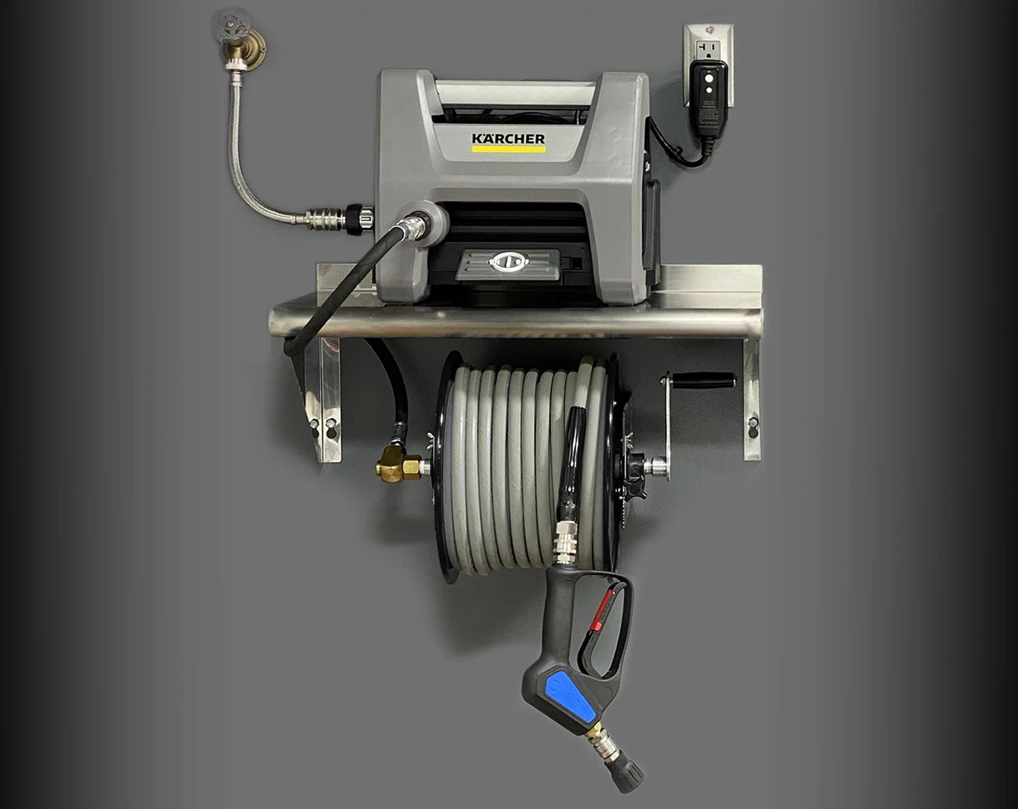 A Kärcher pressure washer with a spray gun, hose, and accessories attached, mounted on a metal cart against a gray background.