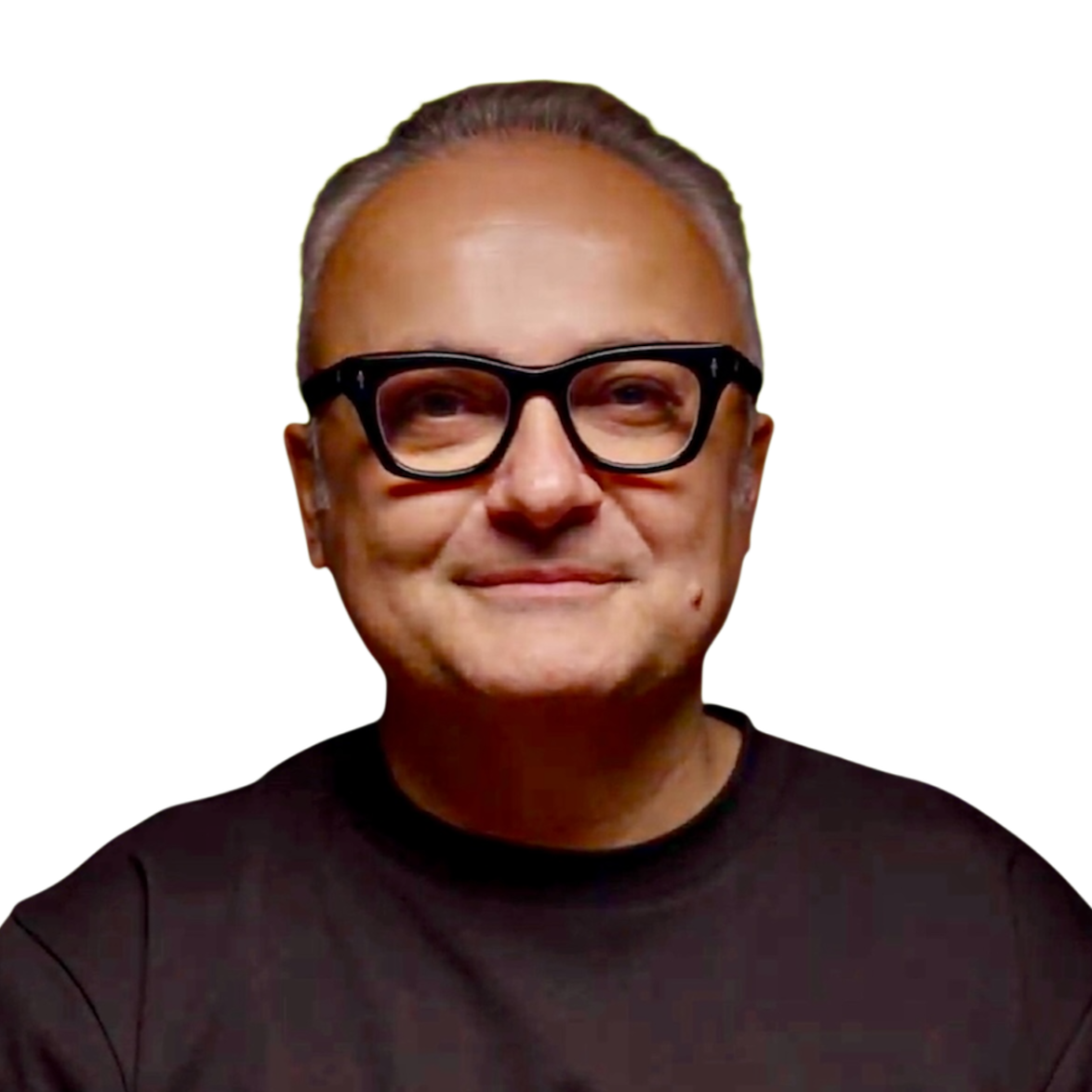 A man with gray hair, wearing large black glasses and a black shirt, smiling against a bright yellow background.