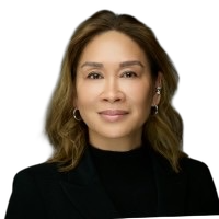 A woman with shoulder-length brown hair, wearing a black blazer and a black top, smiling slightly against a dark background.
