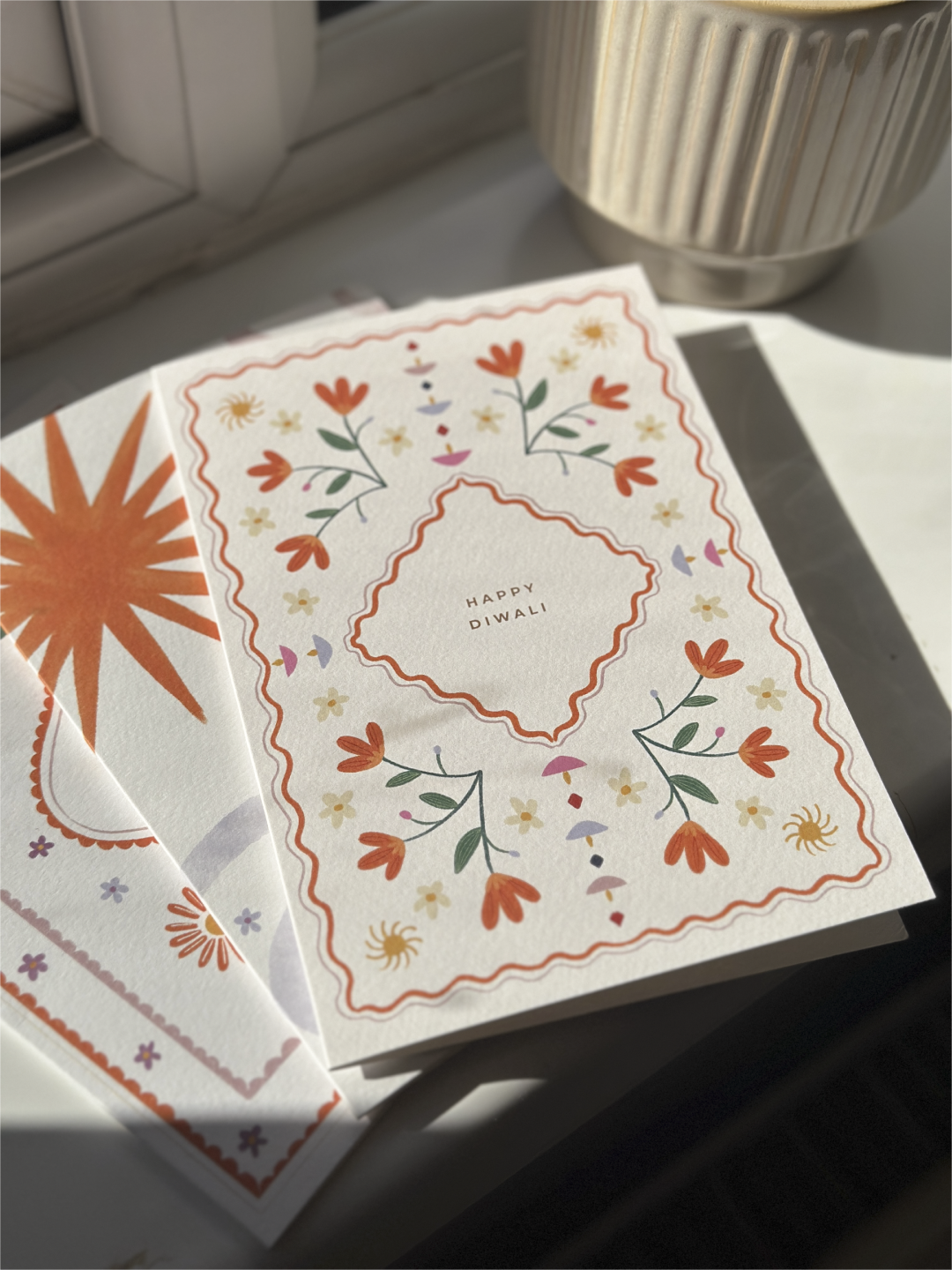 Dragonfly greeting card with floral design and 'Happy Diwali' message on a white surface near a floral-patterned bowl.