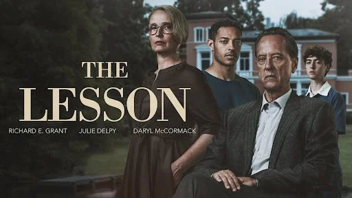 Verschiedene Menschen stehen draußen vor einem Haus, im Hintergrund Bäume und Himmel, mit dem Text ‚The Lesson‘ und die Namen Richard E. Grant, Julie Delpy, Daryl McCormack.