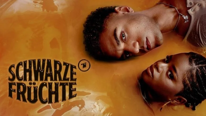 Ein Mann und eine Frau liegen in einer orangefarbenen Flüssigkeit, daneben ist das Logo 'Schwarze Früchte'.