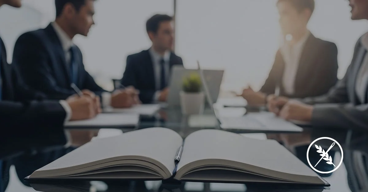 Open notebook in front of a conference table with business men and women