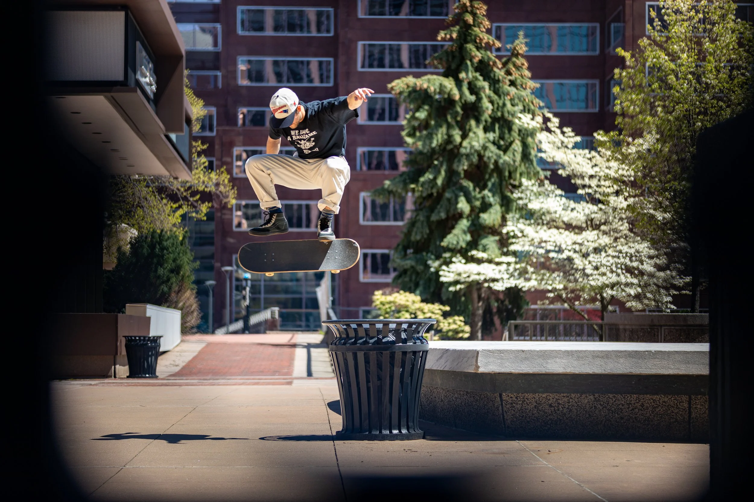Skateboarding kickflips over trash can in Hartford, Connecticut. Photographed by Tyler Baker from Tyler Baker Photo.
