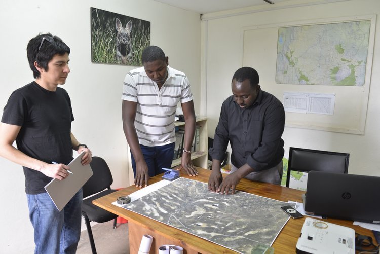   Bernard (center) and Samuel (right) pointing out the different vegetation types at Ol Pejeta visible in the satellite image  