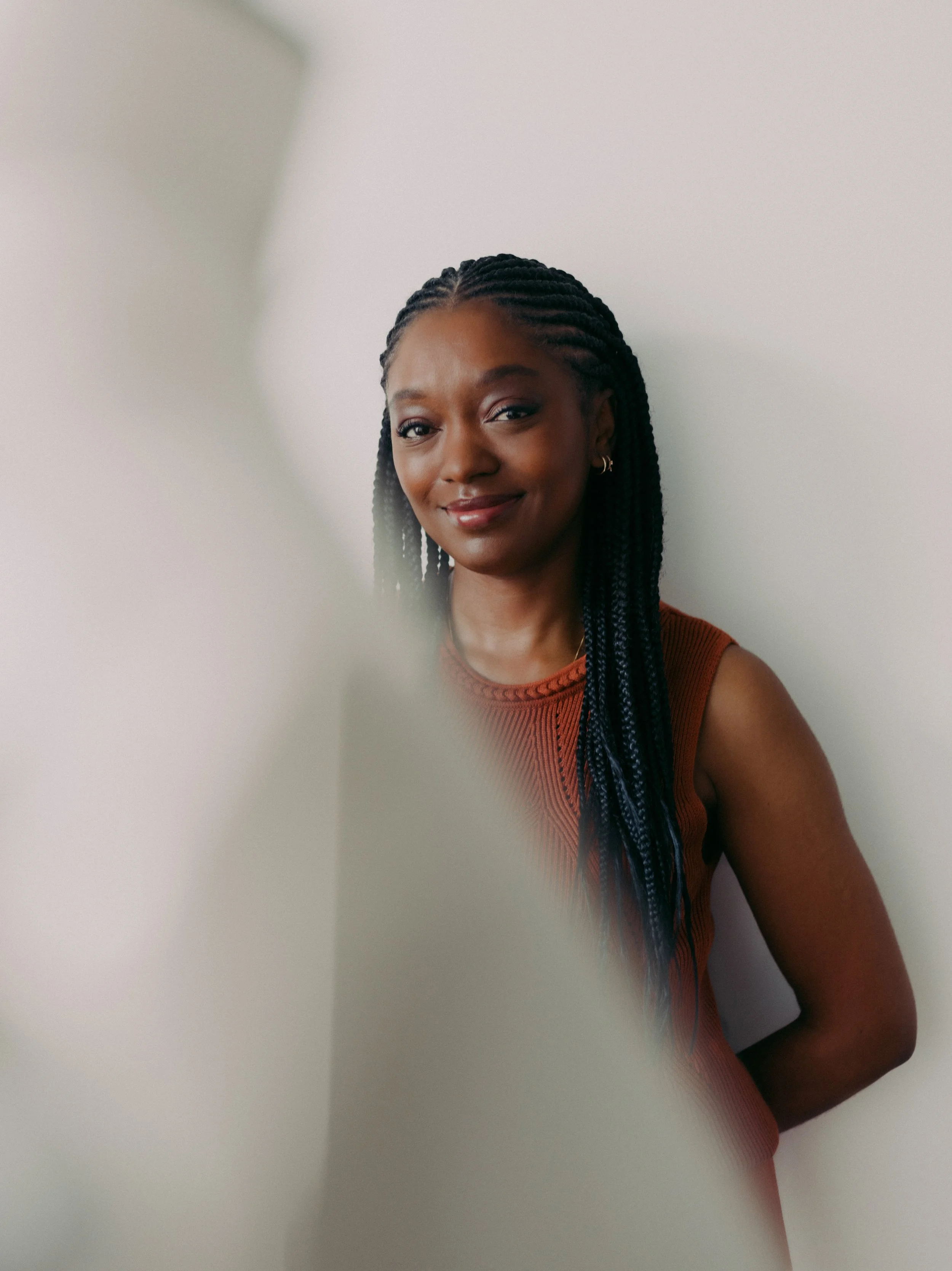 Gladys femme noire, souriante avec des tresses. Sur un fond blanc.