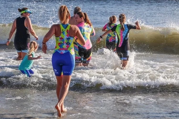 Athletes run into the ocean