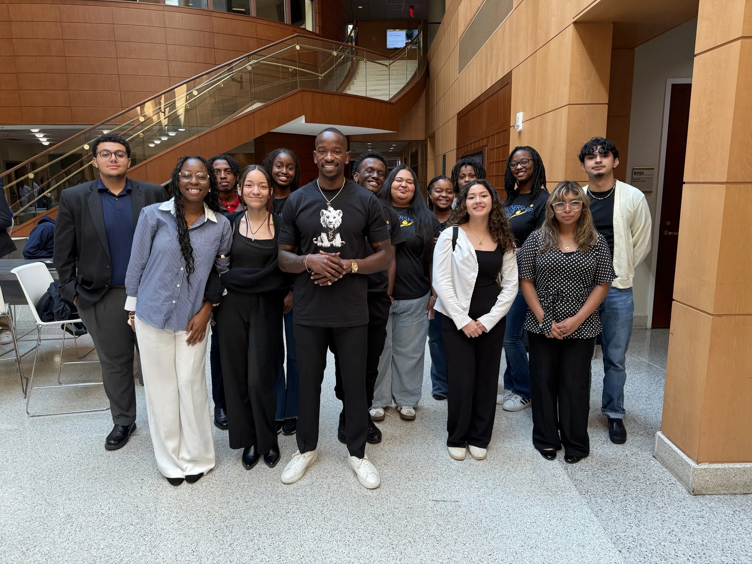 “Charleston Girley standing with a diverse group of young adults inside a modern building, smiling at the camera.”