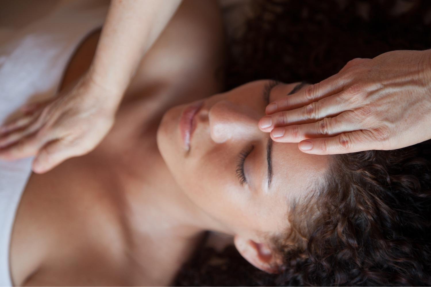 Person receiving a facial massage with their eyes closed.