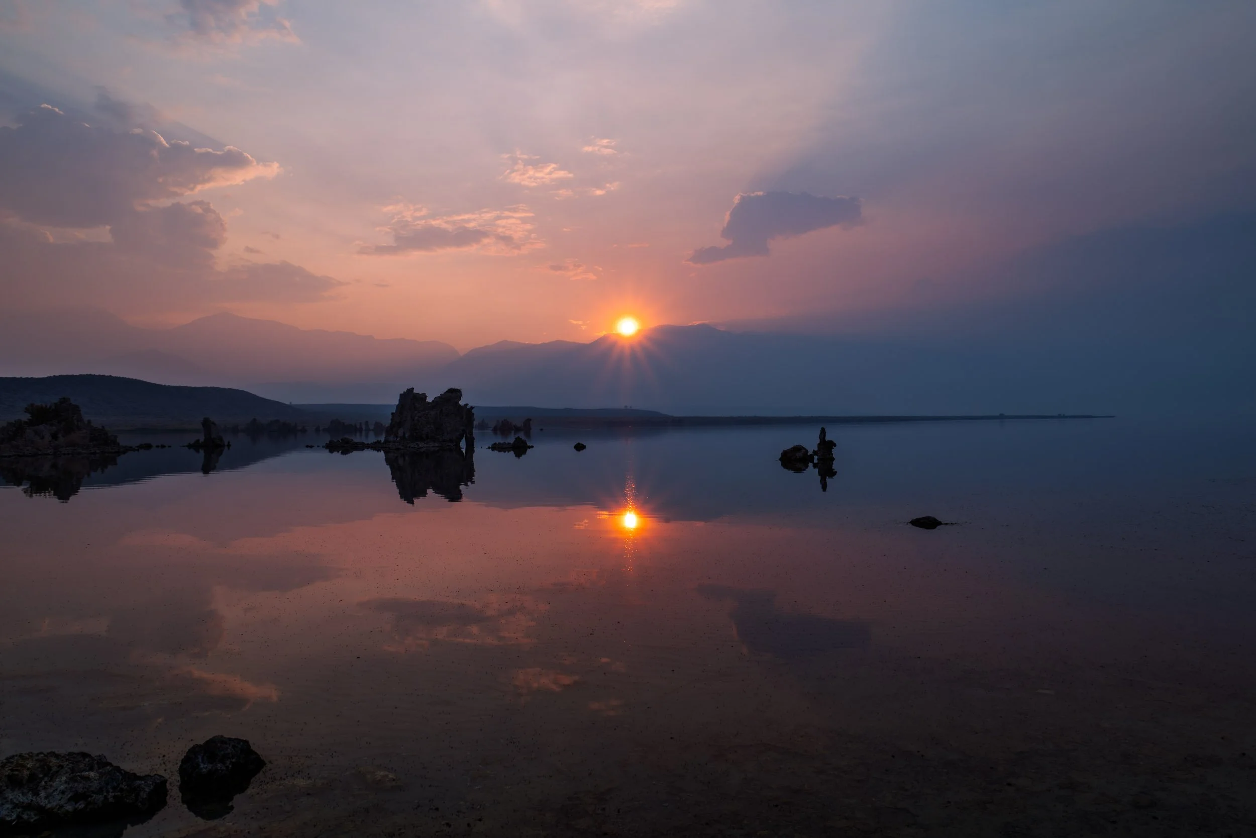 Smokey Calmness: sunset over Mono Lake
The sun sets below the crest of the Sierra Nevada as seen from Mono Lake.  Smoke from a distant wildfire filles the air in a light blanket of smoke.  The particulate matter attenuates the sun, allowing for this 