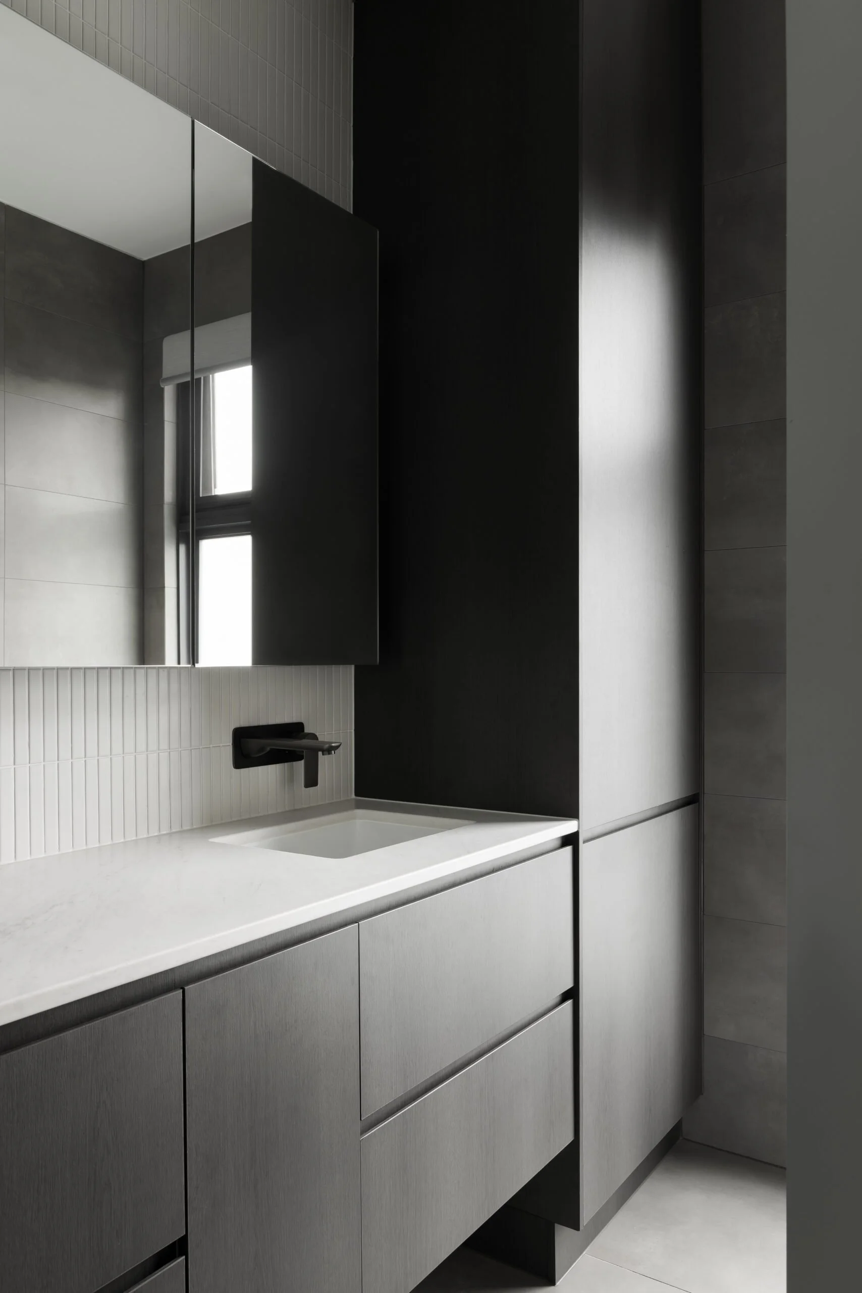 Contemporary Melbourne apartment bathroom featuring a floating vanity, black cabinetry, textured wall tiles and a restrained material palette that creates cohesion across multiple residences.