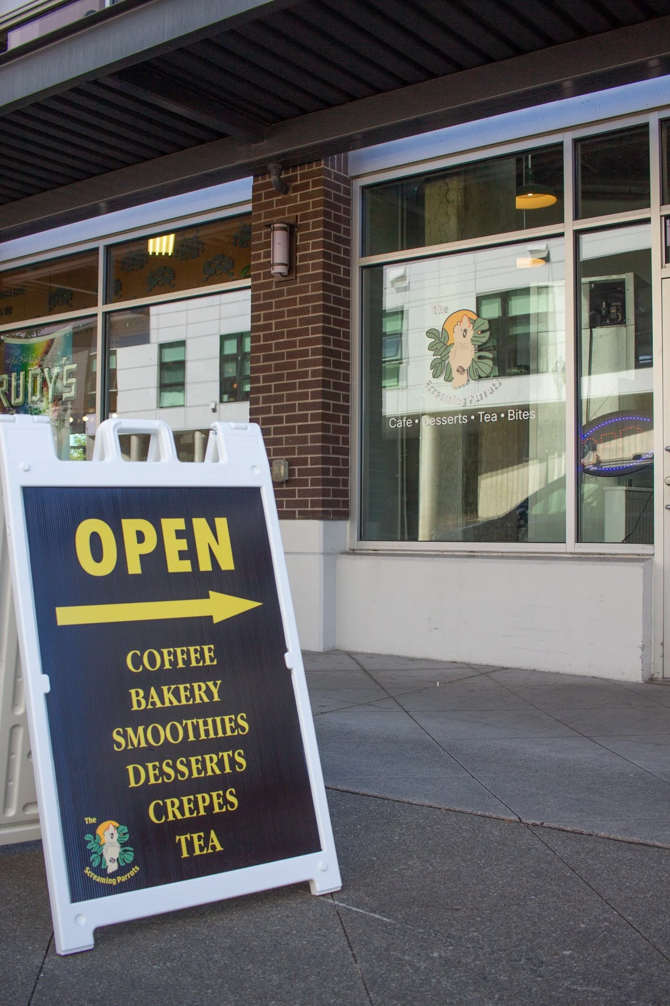 A sign on Cleveland Street advertising coffee, bakery, smoothies, desserts, crepes, and tea.