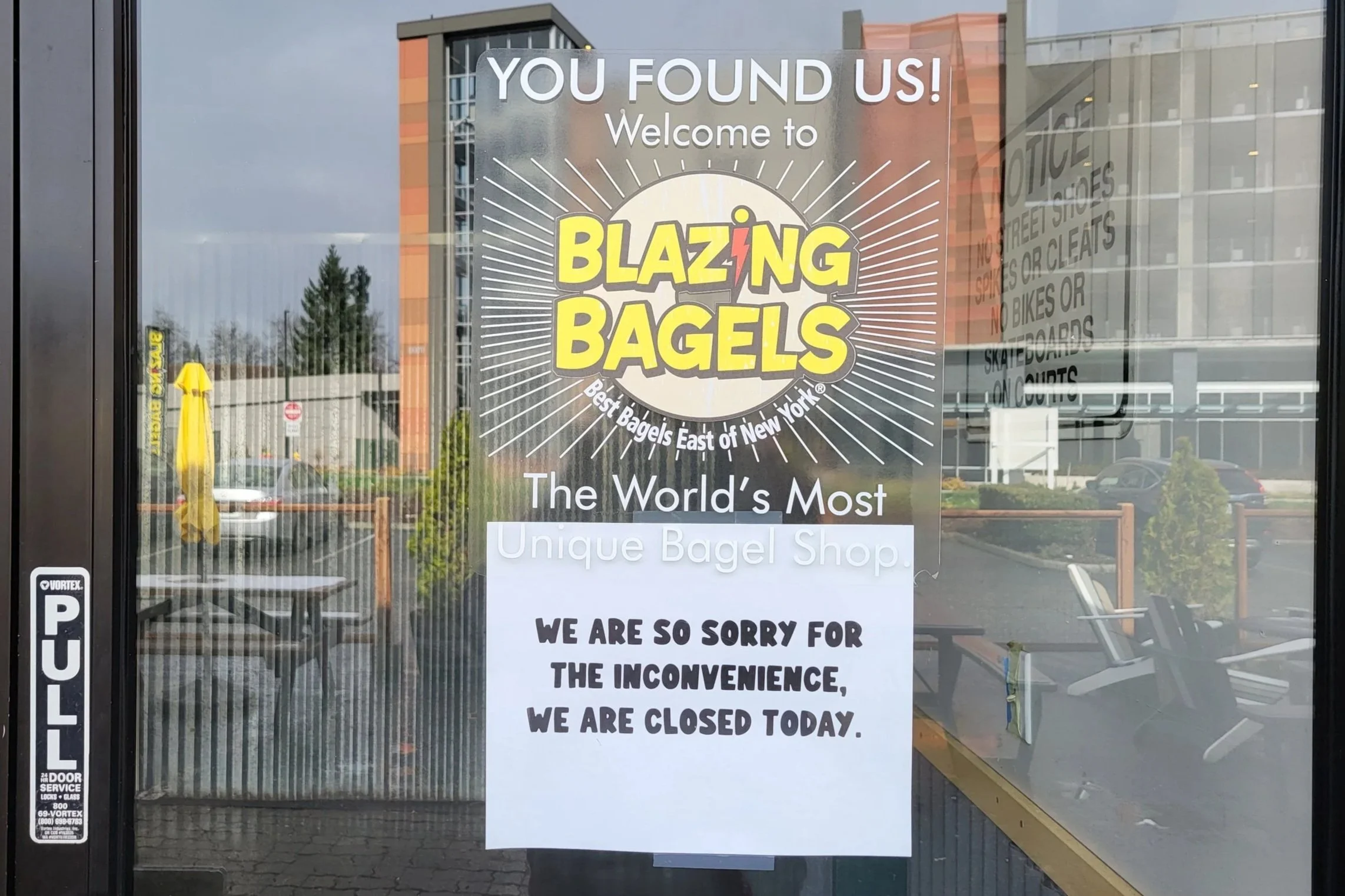 The door of the Redmond Blazing Bagels location with a sign taped to it that reads We are so sorry for the inconvenience, but we are closed today