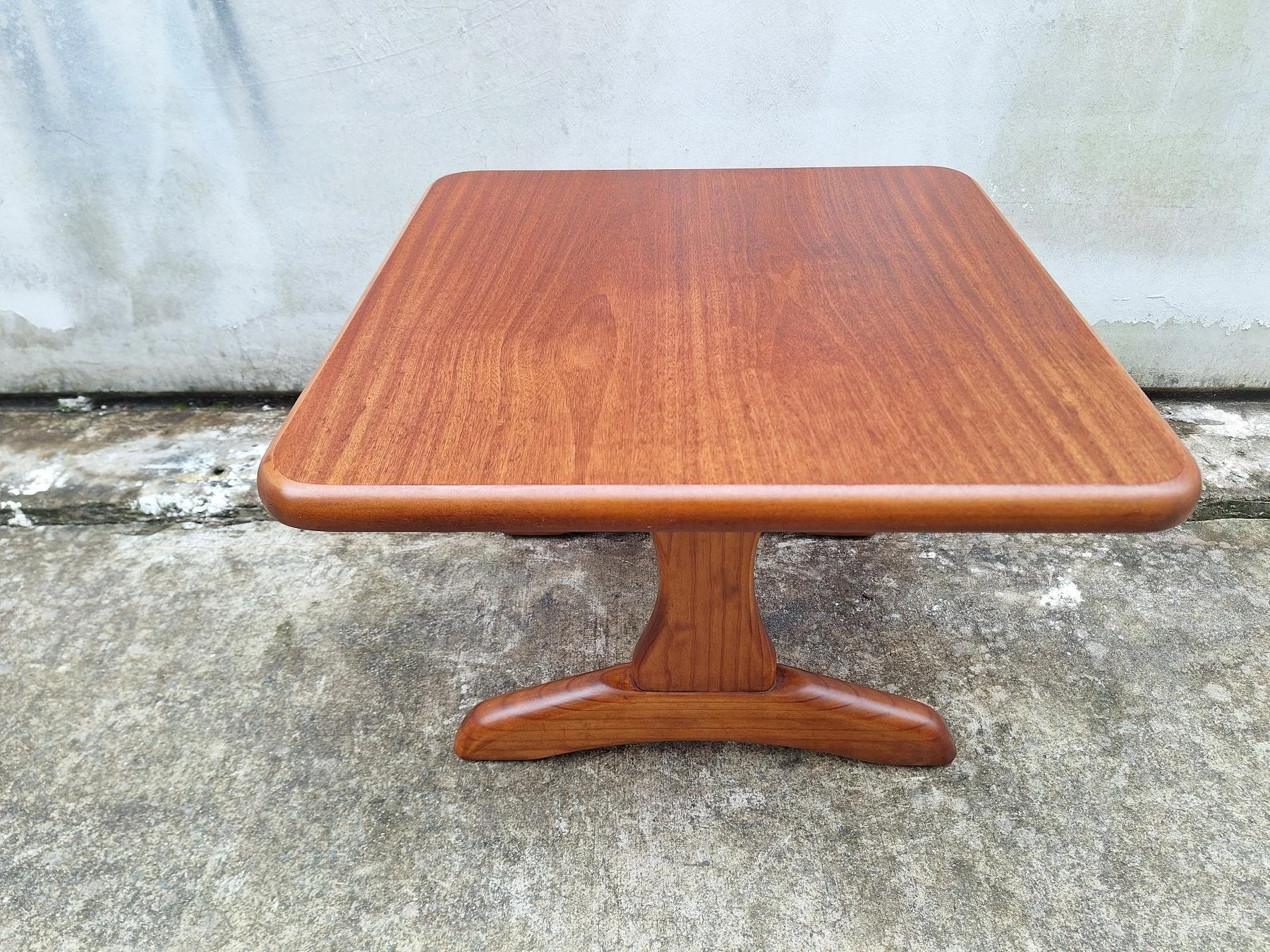 Vintage square timber coffee table with rounded edges and sculptural pedestal base.