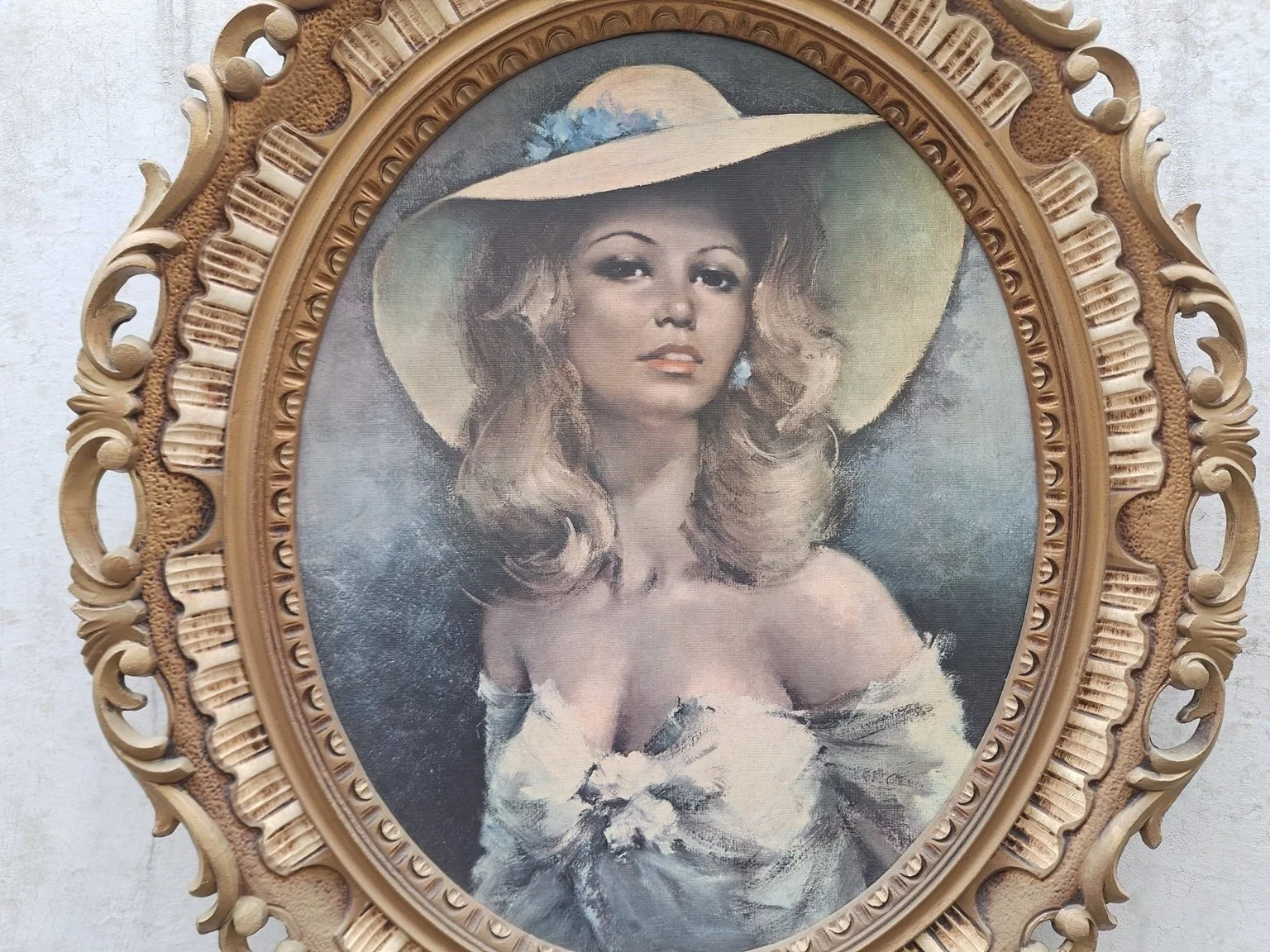 Close view of the woman in a pale hat and floral-trimmed dress, with the textured print surface and decorative frame visible.