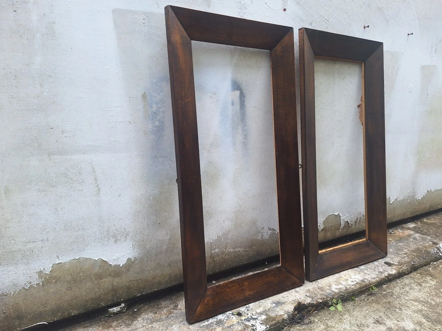 Pair of tall vintage timber frames viewed at an angle, showing broad dark timber profiles.
