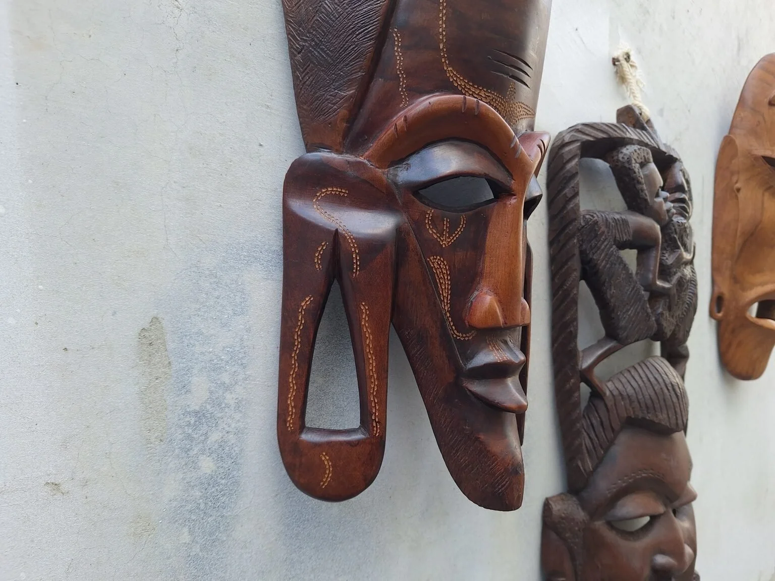 Three-quarter view of the elongated carved timber wall mask showing its sculptural depth.