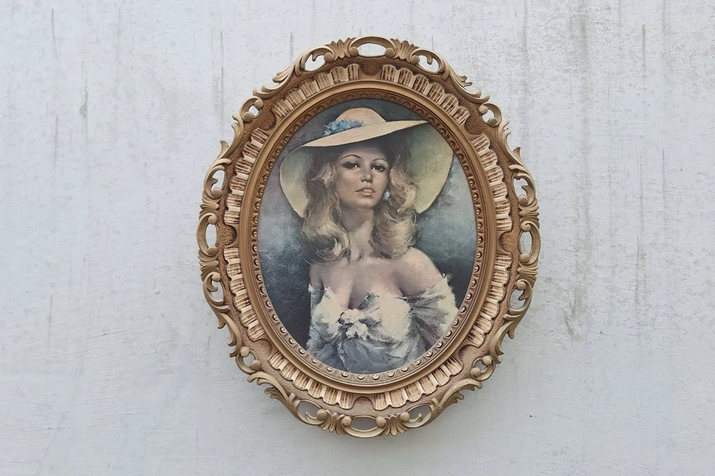 Vintage oval portrait print of a woman in a wide-brimmed hat, in an ornate gold-tone frame.