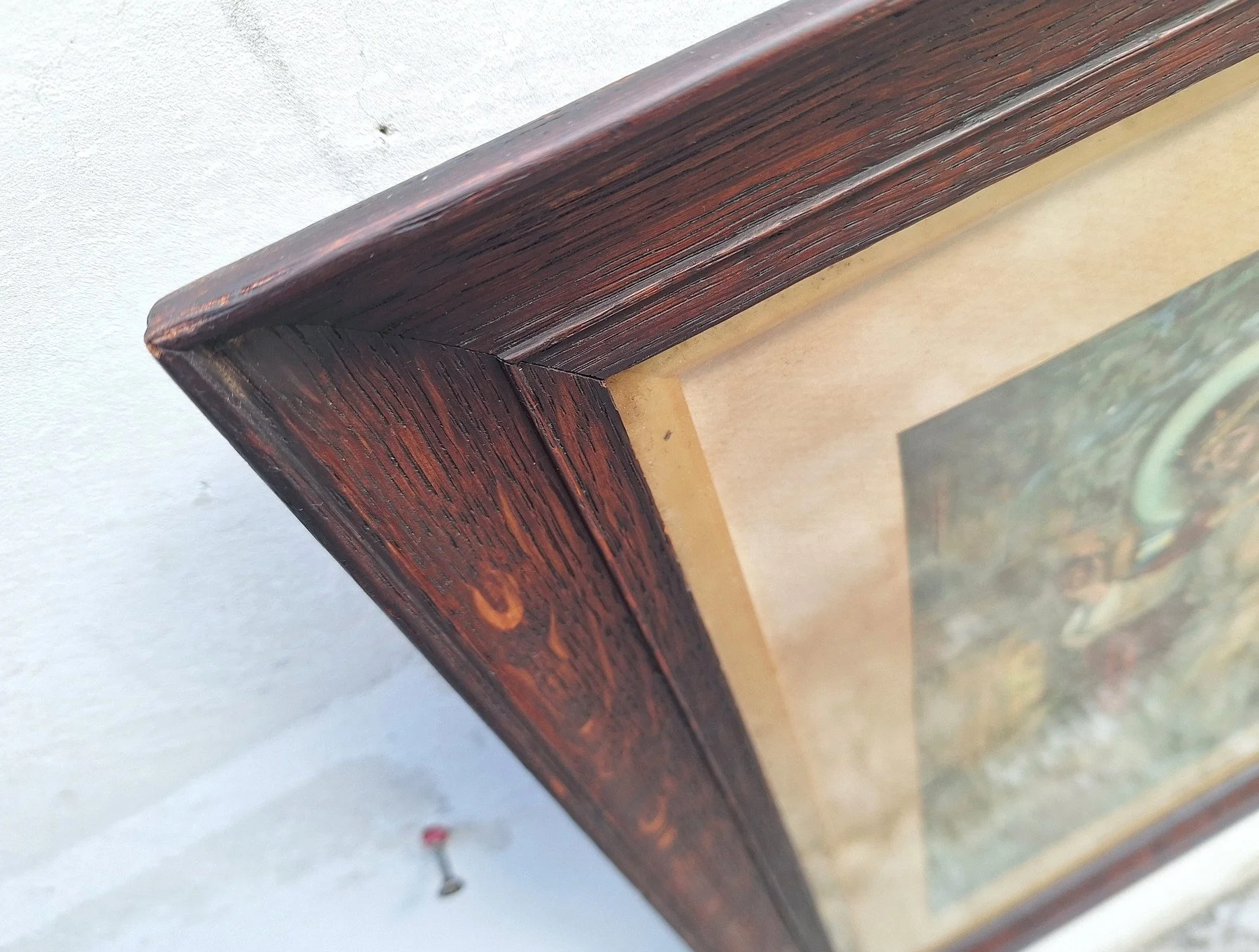 Angled view of a vintage Good Shepherd print behind glass