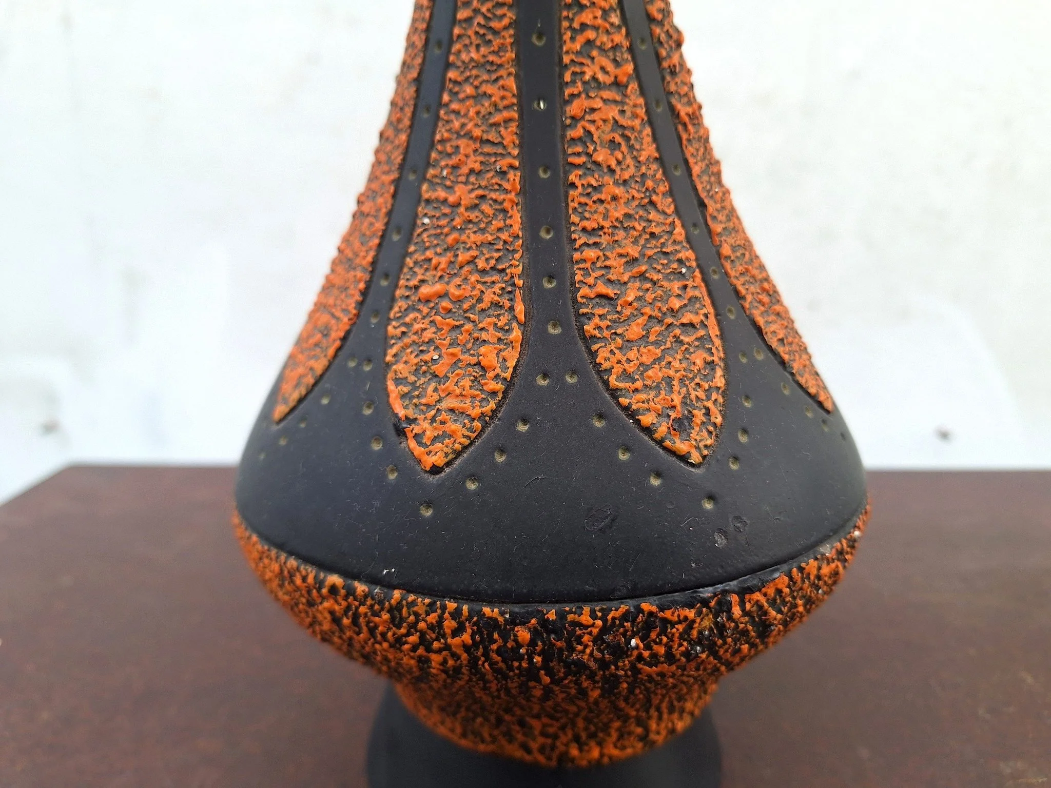 Detail of textured plaster lamp base with orange and black finish.