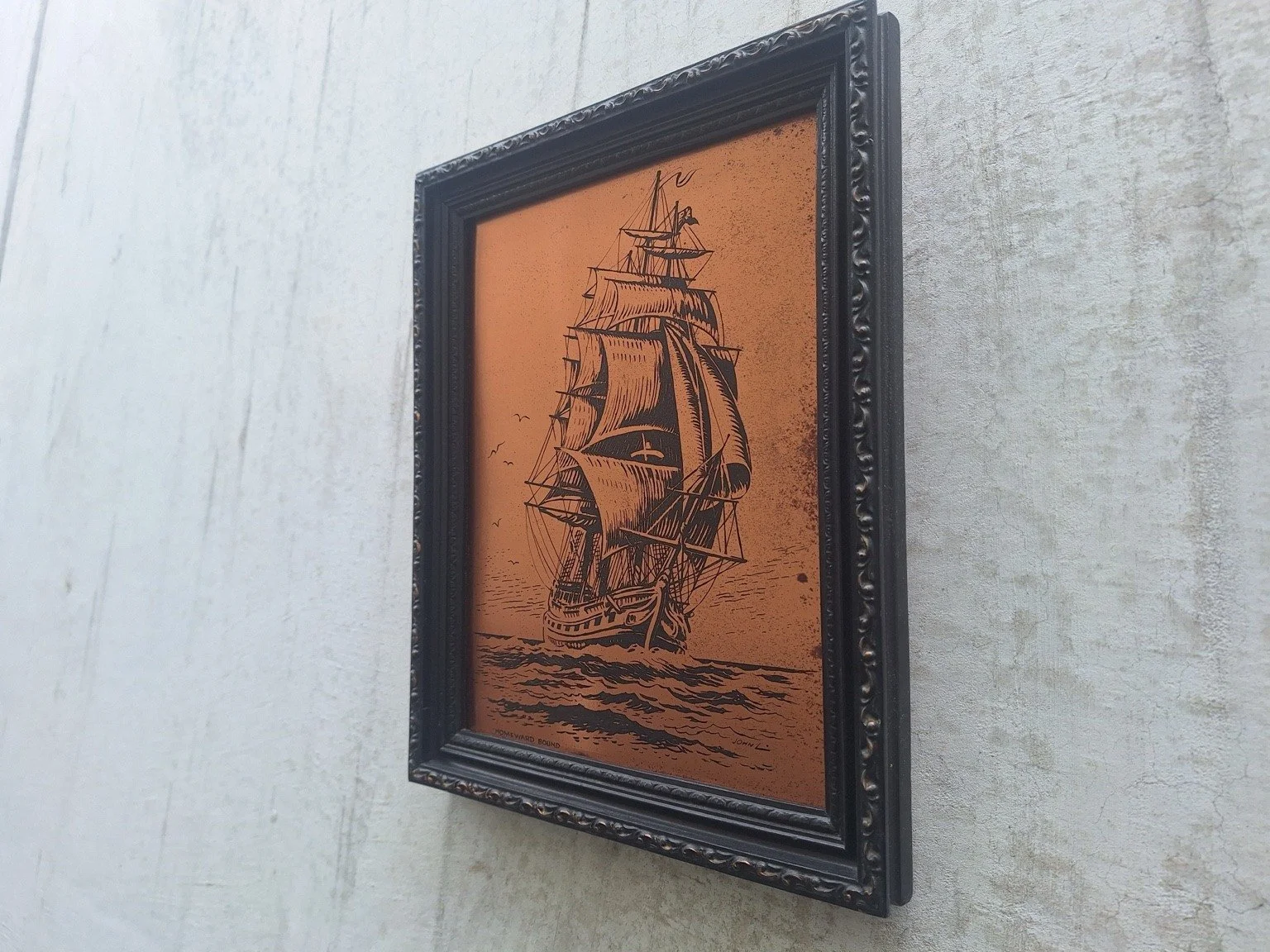 Angled view showing the copper ship artwork and depth of the dark frame.