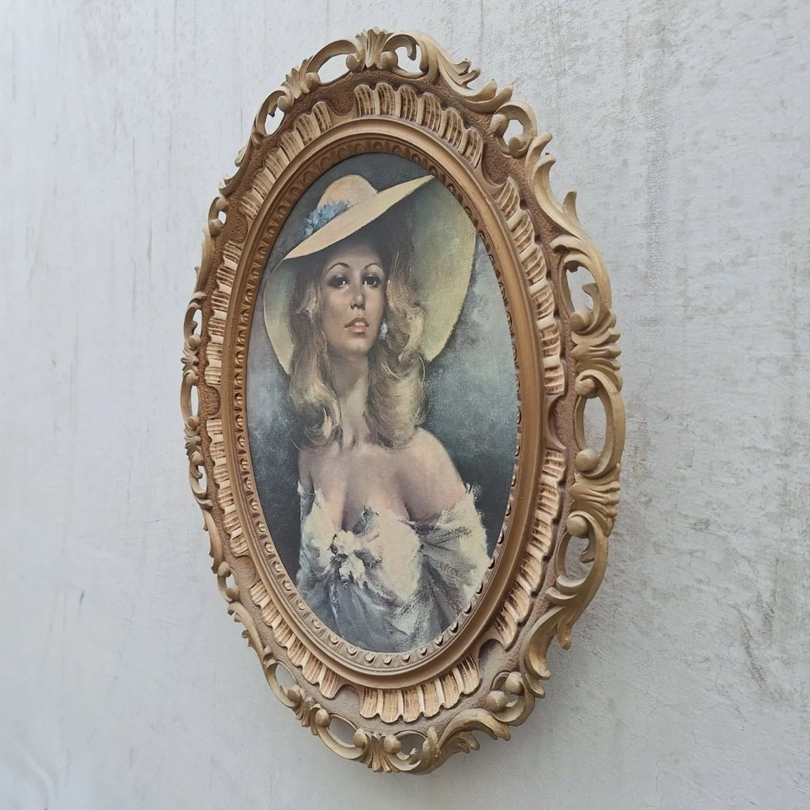 Angled view showing the depth and open scrollwork of the oval gold-tone portrait frame.