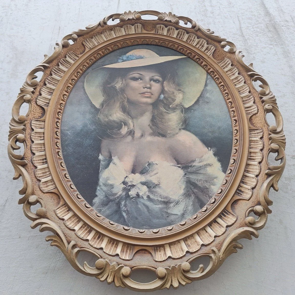 Low-angle view of the portrait print and layered lower edge of its ornate oval frame.