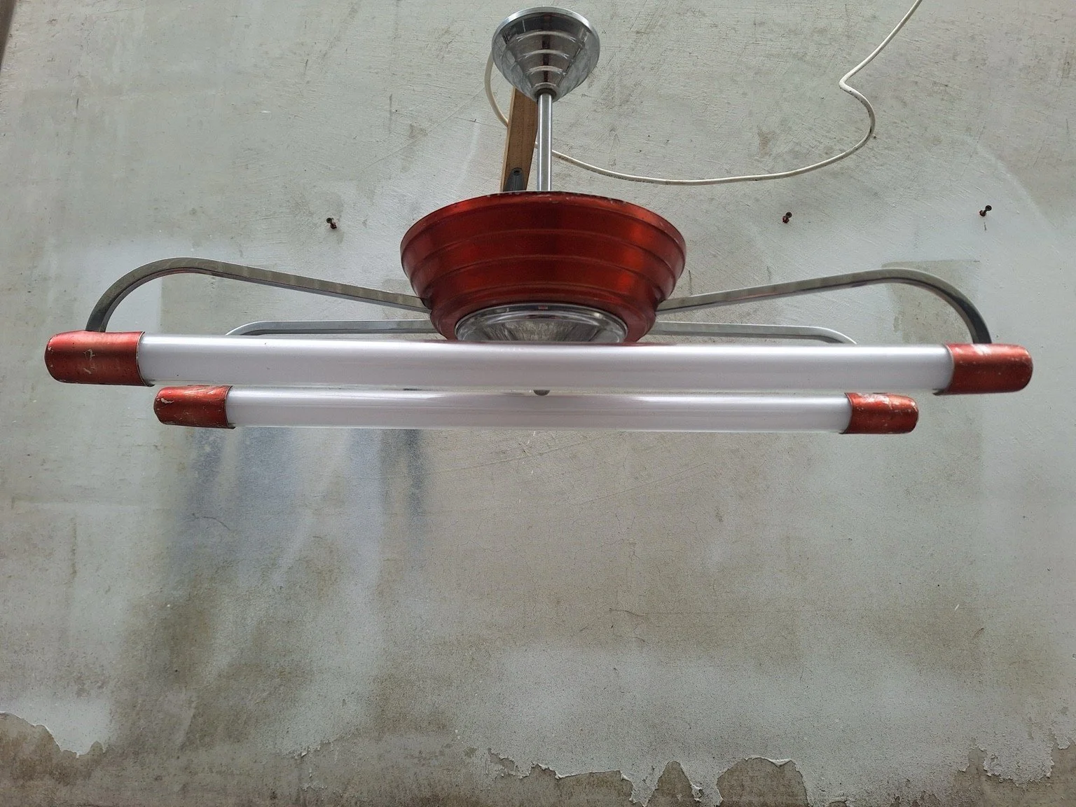 Front view of the red and chrome twin-tube ceiling light, showing two parallel white tubes and a stepped central housing.