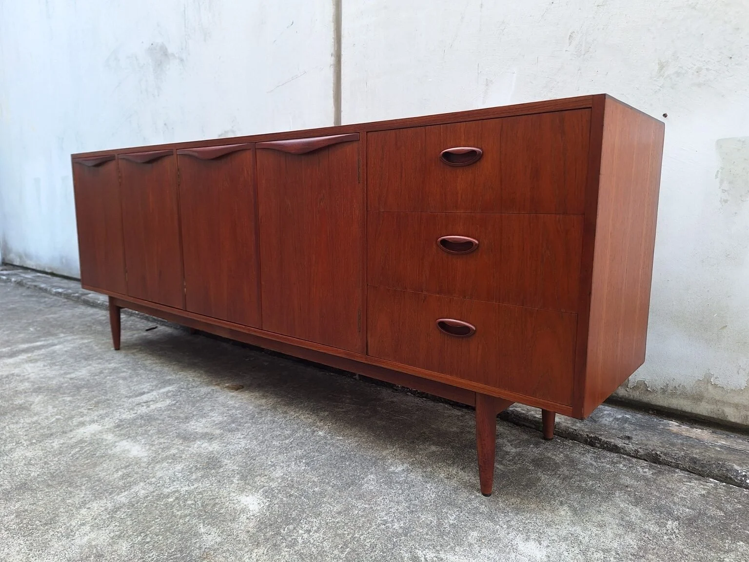 Right three-quarter view of the restored Chiswell wave handle teak sideboard.