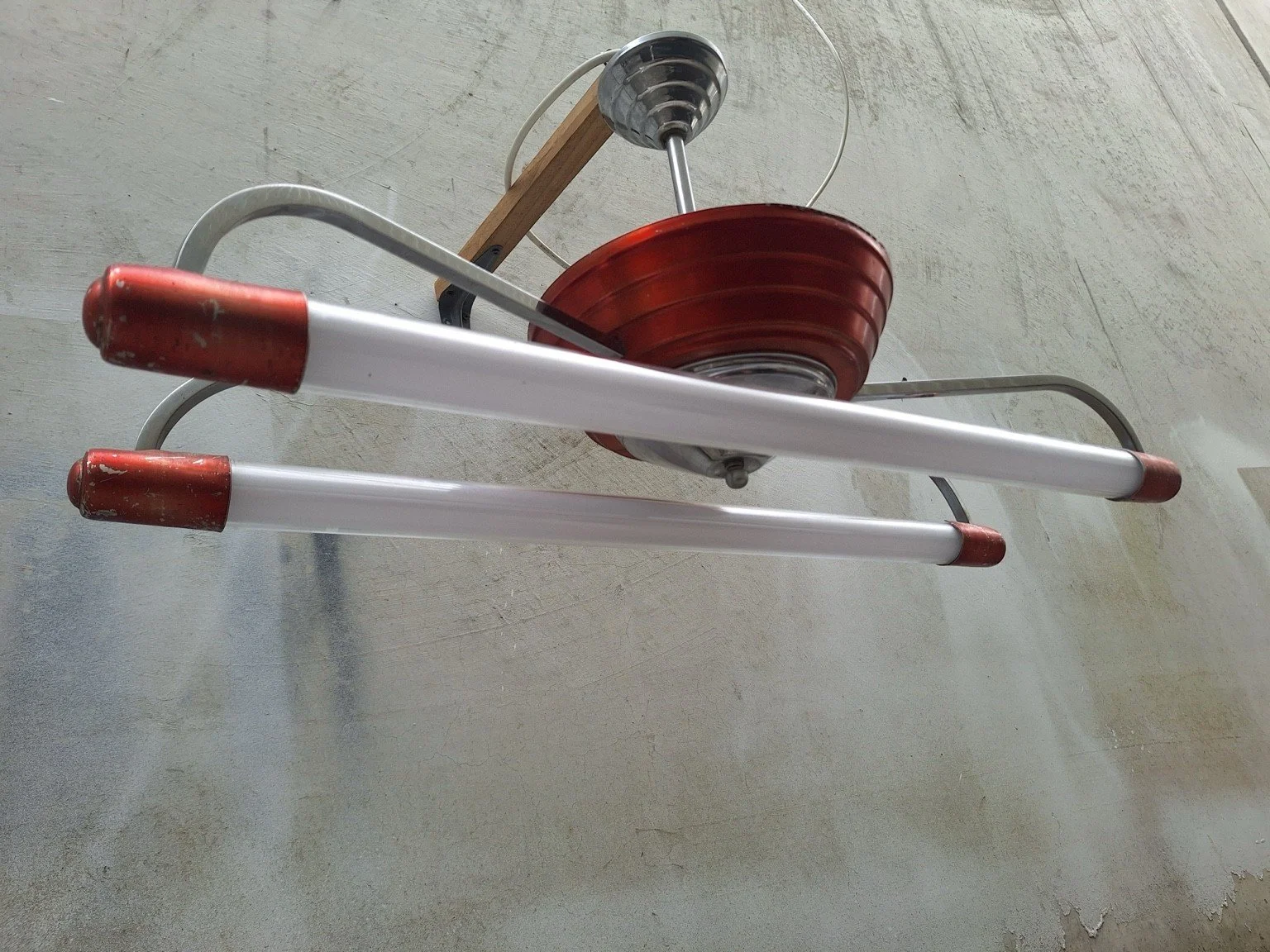 Angled view of the twin-tube ceiling fitting showing curved silver-tone supports and red end caps.