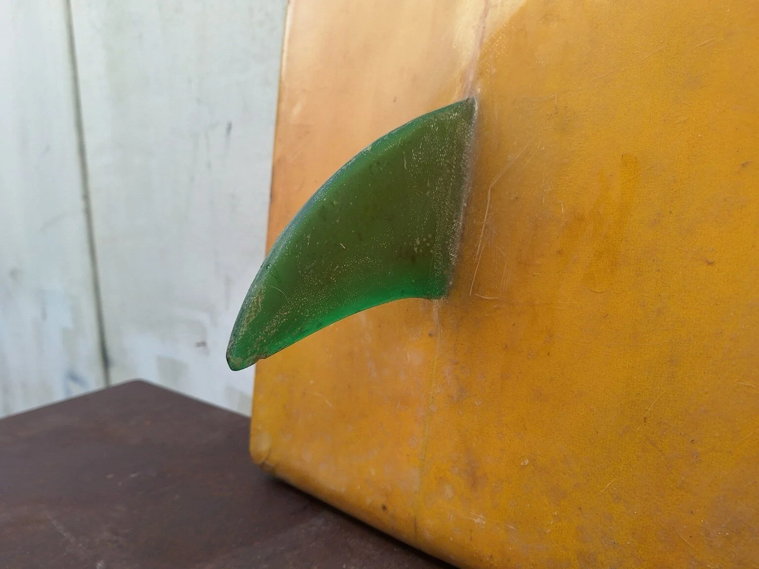Close view of wear and surface losses around the red nose of the vintage surfboard.