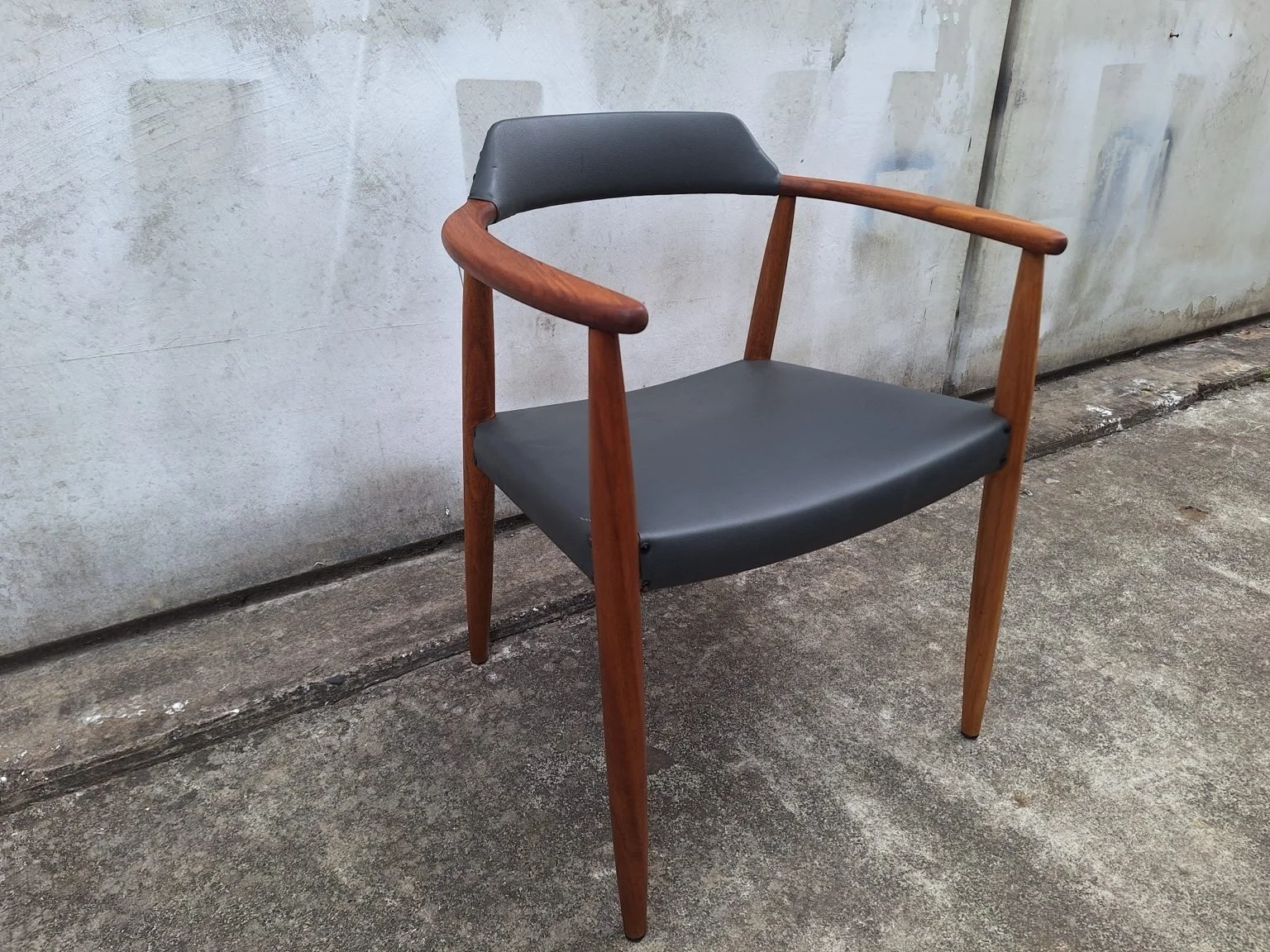 Opposite front angle of the armchair showing the timber frame and upholstered seat and backrest.