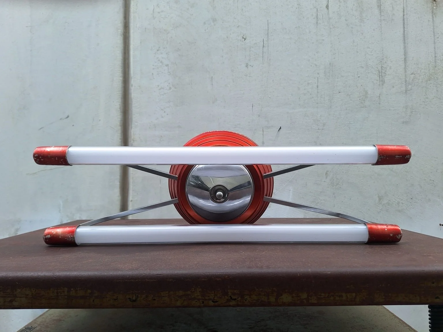 Close front view of the stepped red central housing, curved supports and parallel tubes.