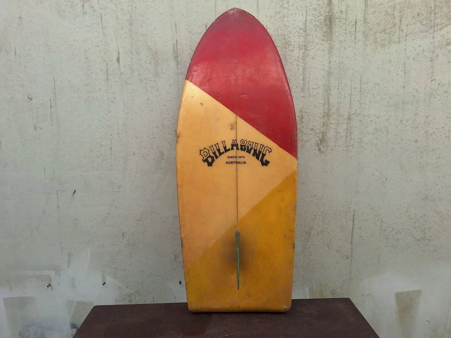 Close view of the green single fin and worn underside of the vintage surfboard.