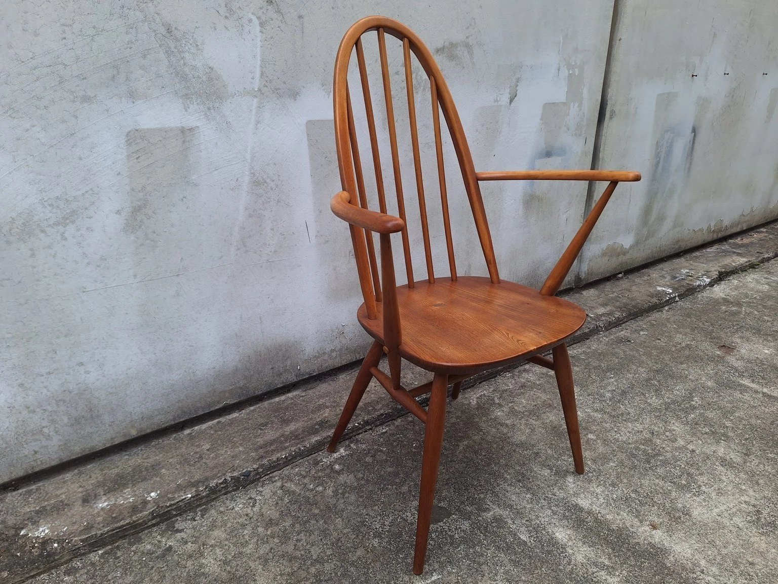 Ercol Windsor carver chair with tall spindle back, shaped timber seat and curved arms, viewed from the front at an angle.