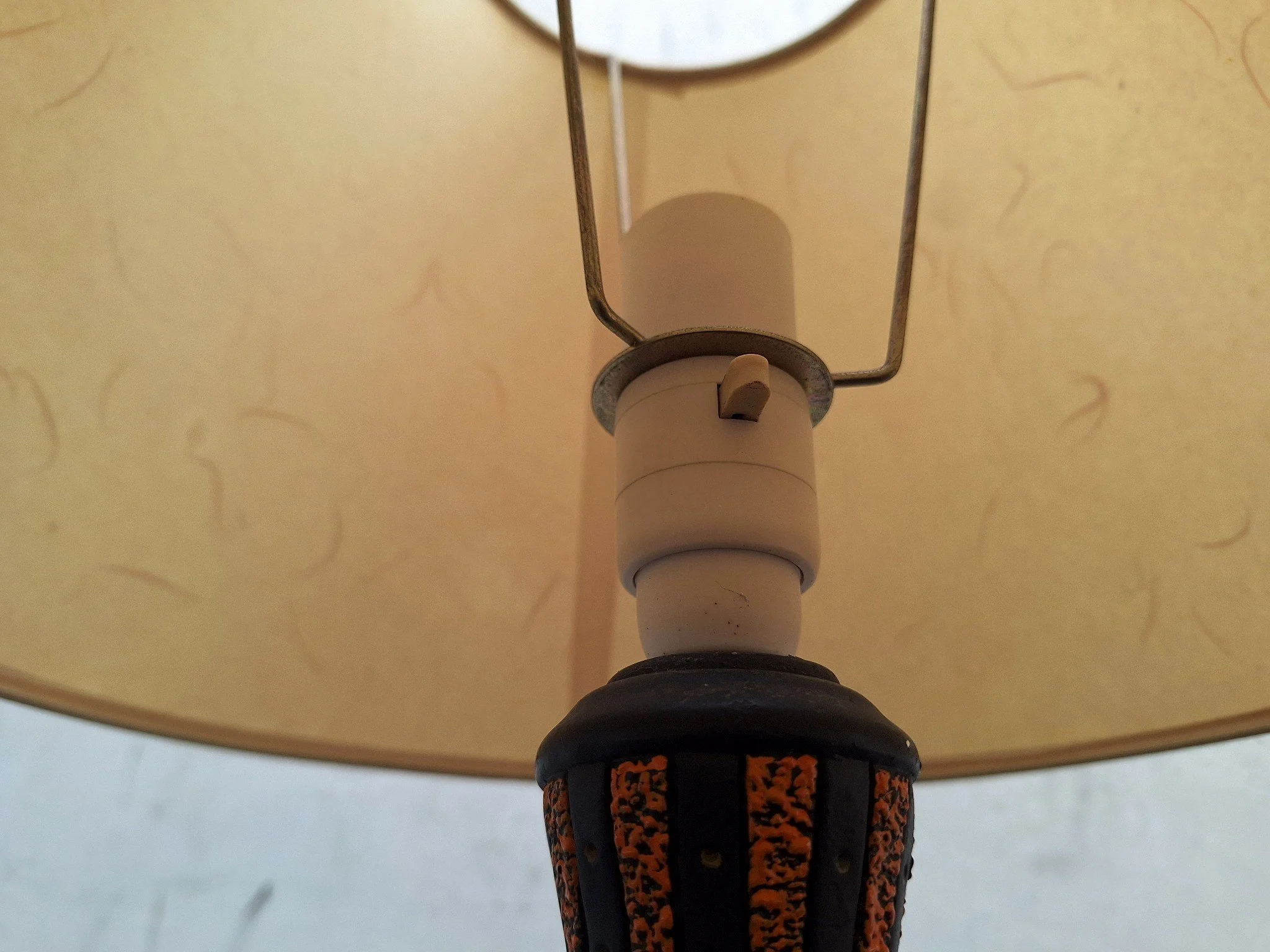 Detail of textured plaster lamp base with orange and black finish.