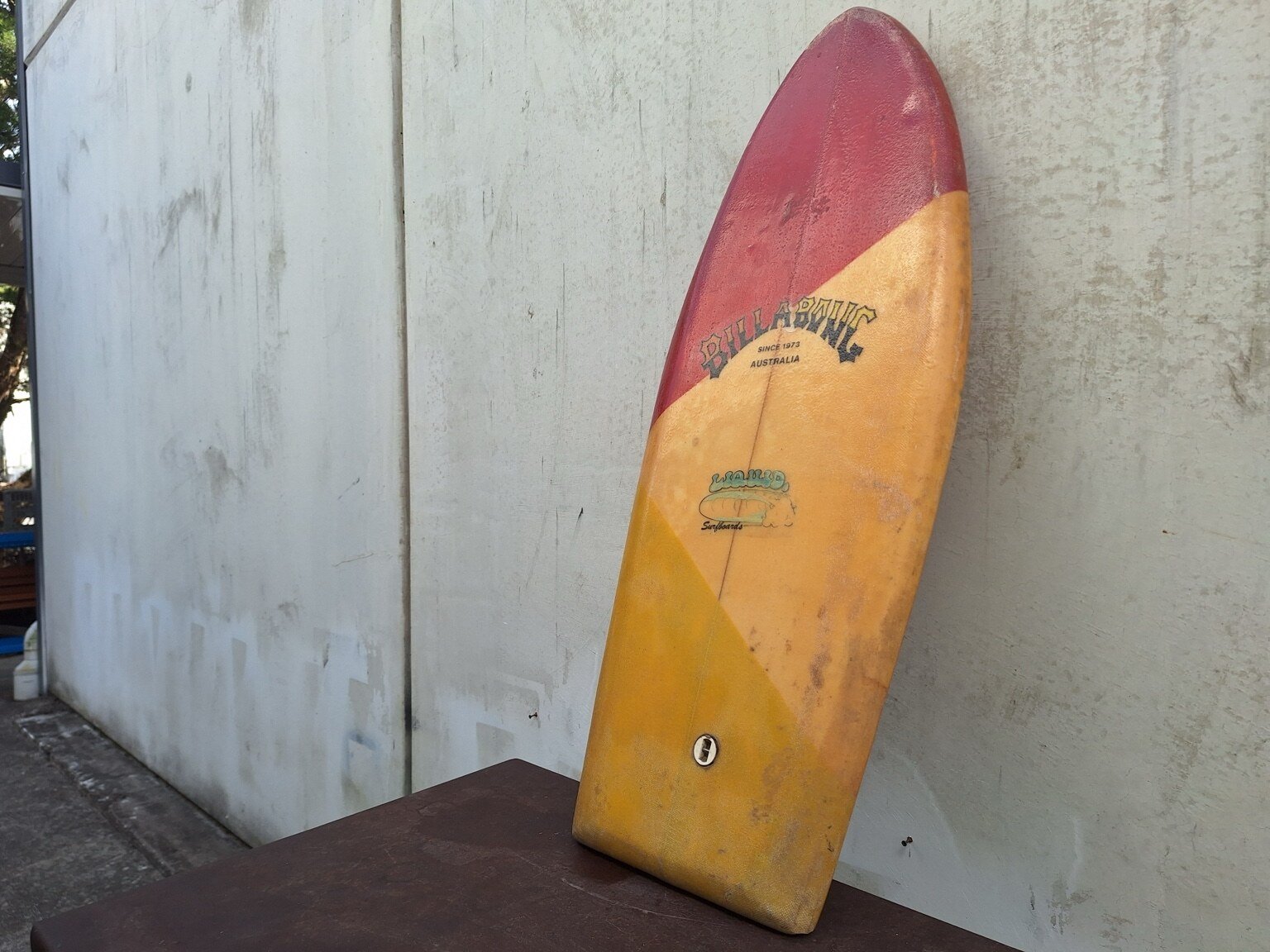 Reverse view of the vintage single-fin surfboard with red, ochre and yellow colour blocking.
