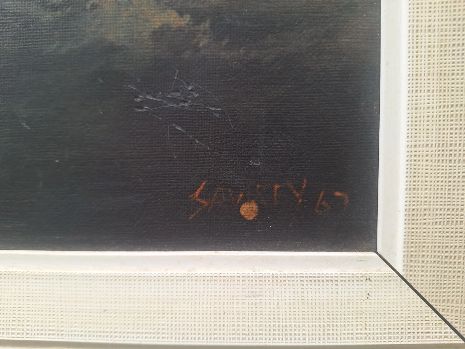 Close view of the signature within the image, surface creasing or lifting above it, and textured frame border.